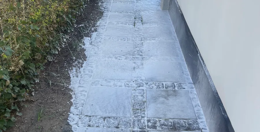 Algebehandling under behandling: spray-lance applicerer algecid på belægningssten