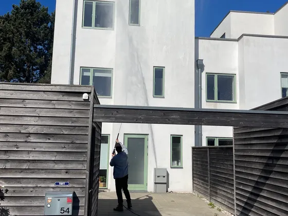 Aktiv Rens medarbejder renser og behandler hvid villafacade fra jorden på Sjælland