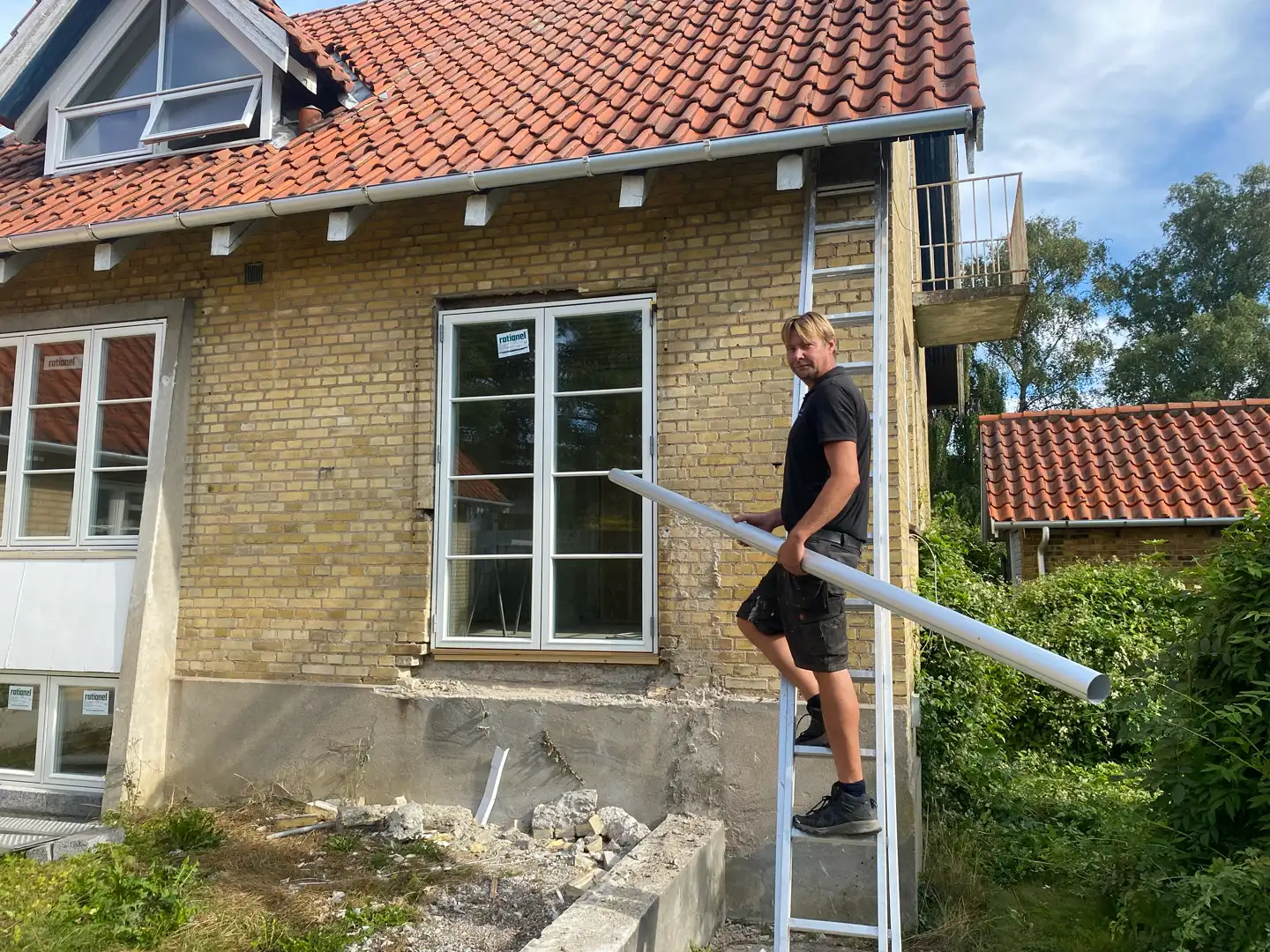 Claus fra Aktiv Rens på stigen med en ny tagrende ved en villa
