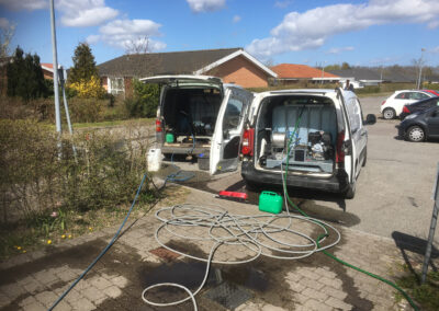 To servicebiler på opgave med professionel fliserens, fjernelse af alger, snavs og belægninger for at give fliserne nyt liv